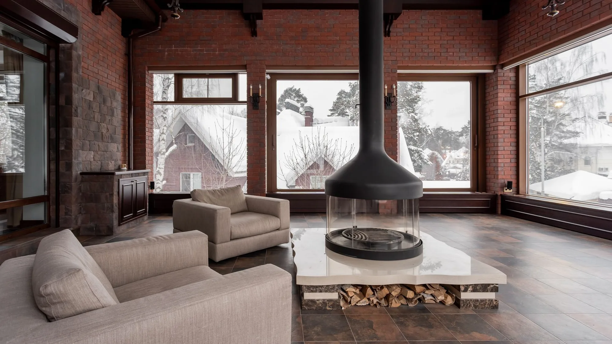 Woonkamer met grote ramen en uitzicht op een besneeuwd landschap