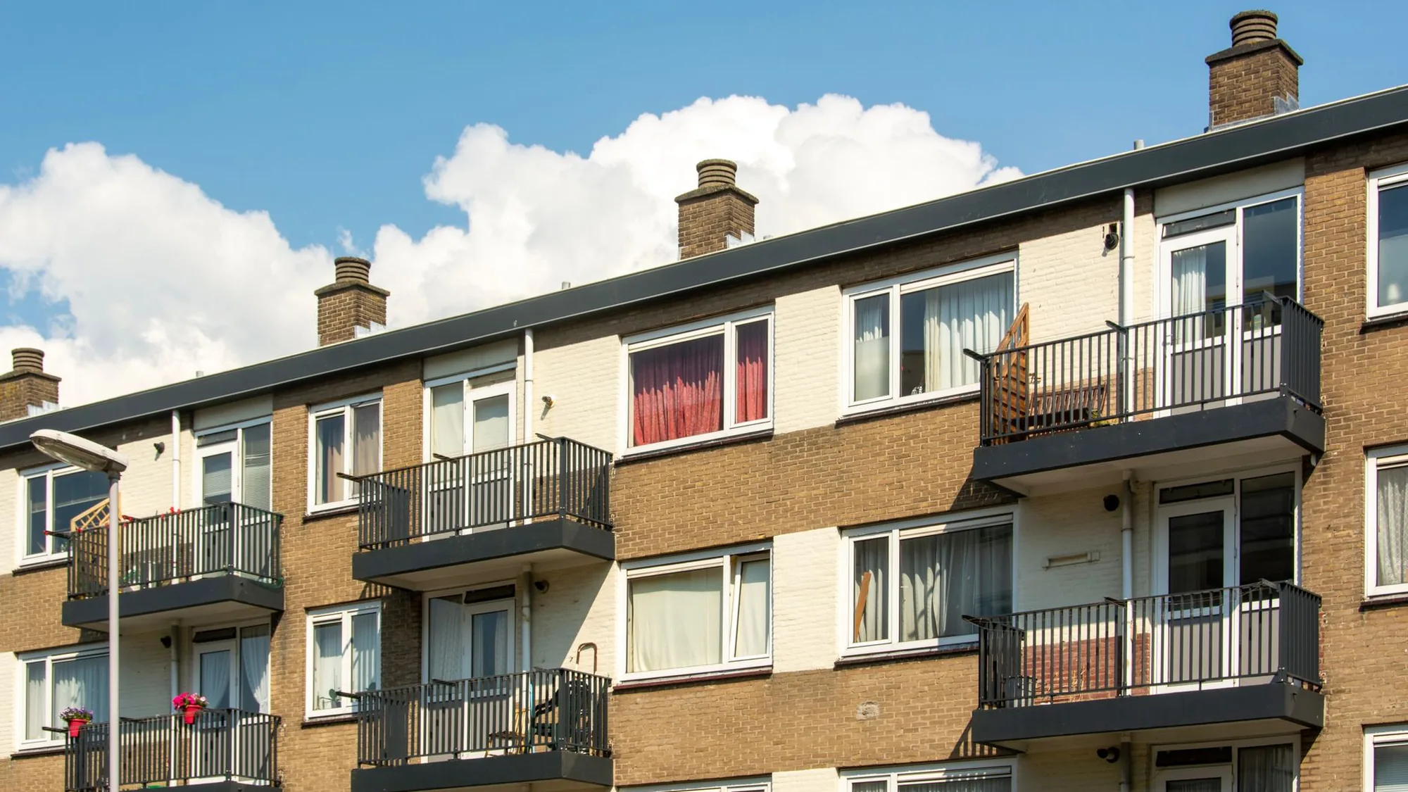 Portiekflat met veel ramen en balkons, typisch bezit van een woningcorporatie